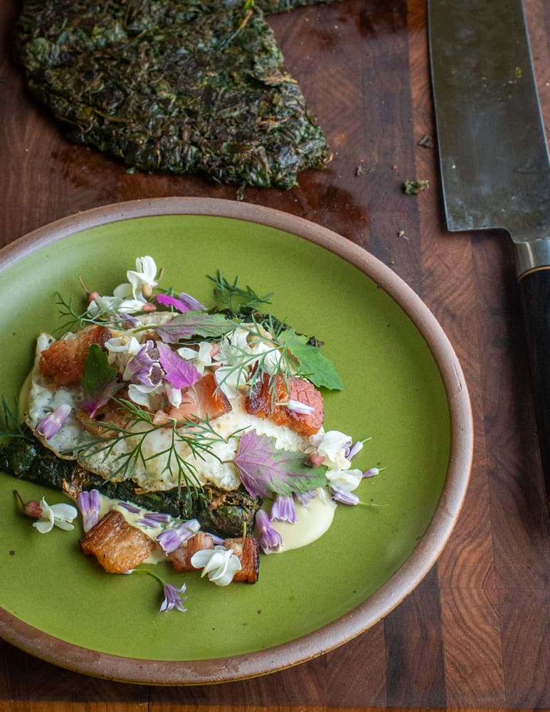 Wild spinach cake with bacon, ramp sauce and wild flowers