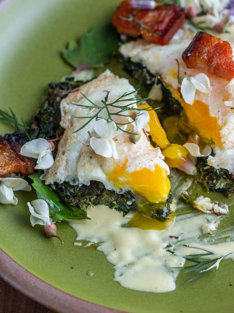 cutting into a runny egg on top of a piece of wild spinach cake