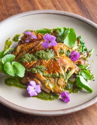 Golden oyster mushroom steaks with edible flowers and watercress on a plate