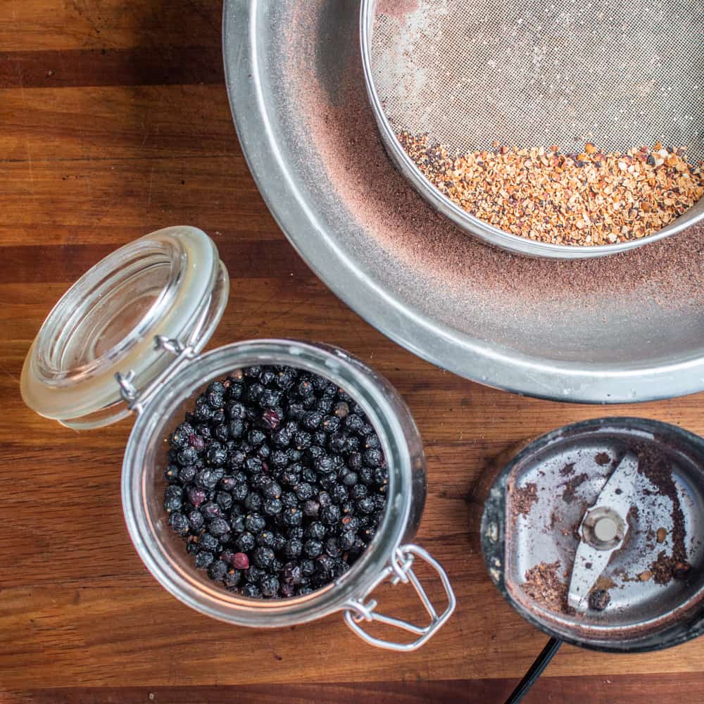 Grinding and sifting dried chokecherries to make bird cherry flour
