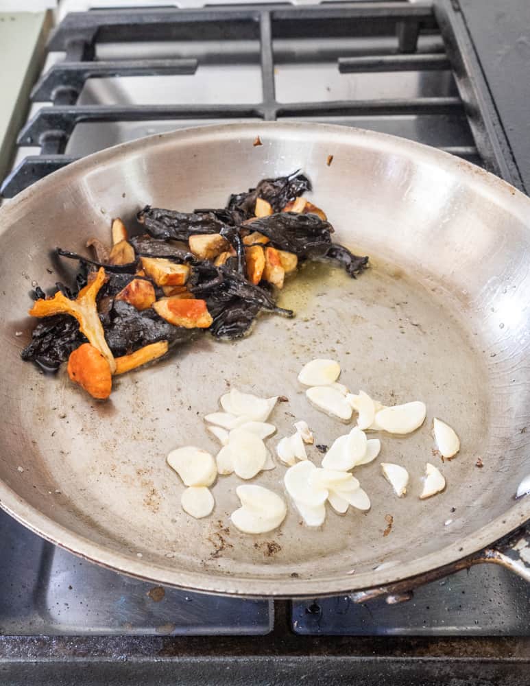 Cooking black trumpet mushrooms and garlic for pasta in a pan