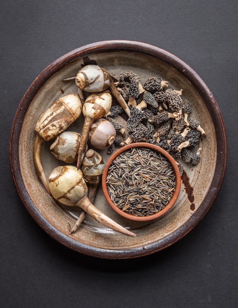 Dried morels, wapato tubers, and wild rice on a plate 