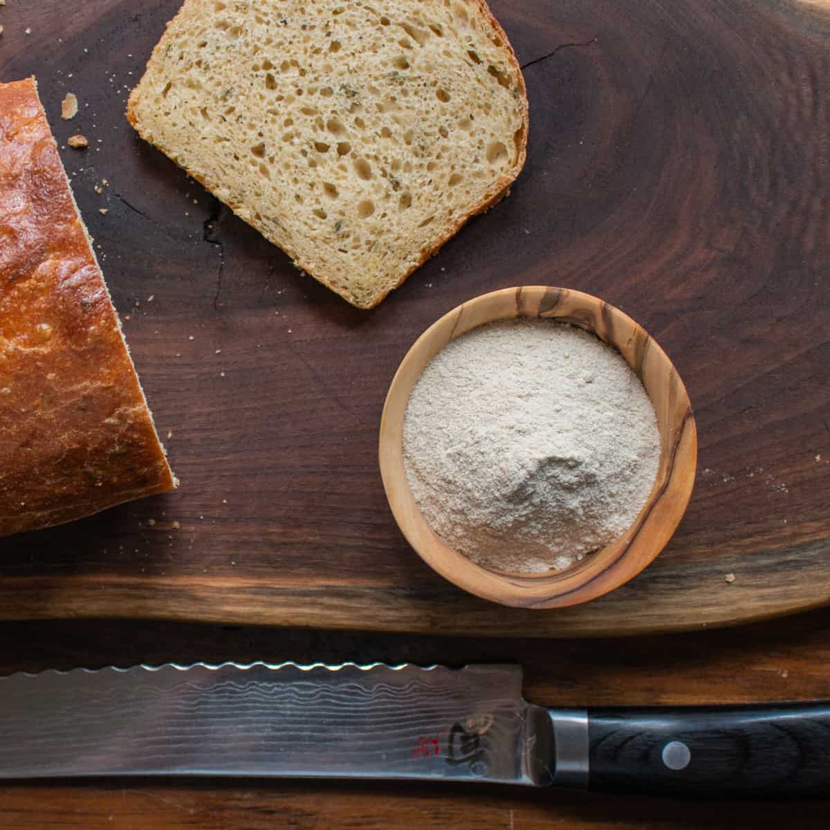 a bowl of amaranth flour next to a loaf of bread. 
