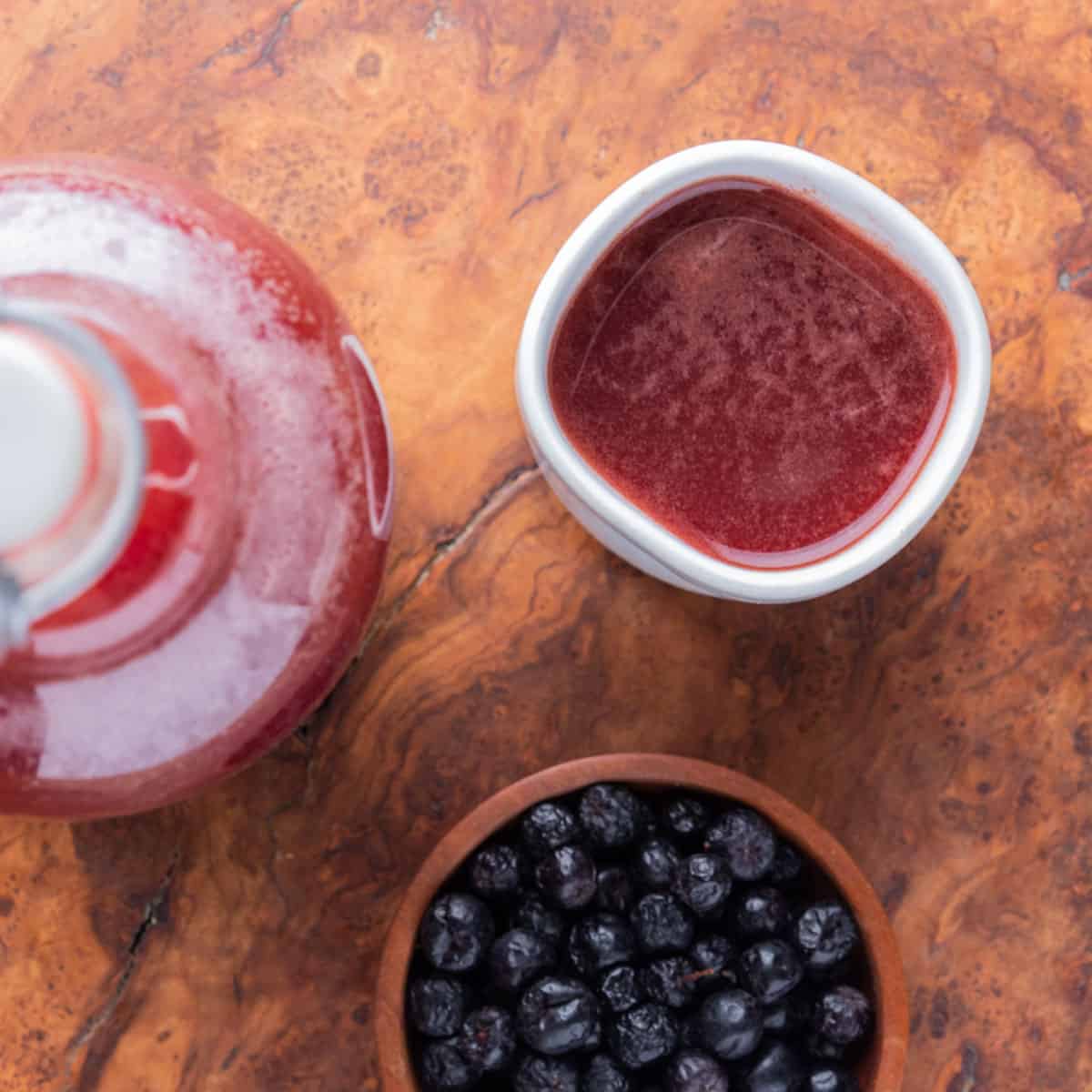 a cup of aronia berry cider next to a bowl of berries