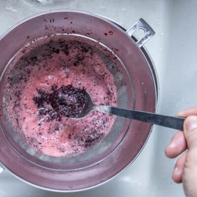 straining aronia berry cider through a chinois