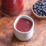 a cup of aronia berry cider next to a bowl of berries