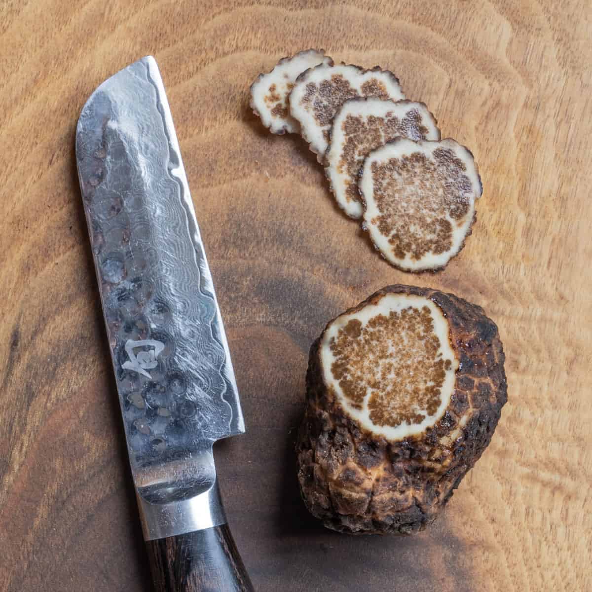 A blue ridge truffle on an oak board, cut with slices fanned out next to a knife