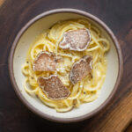 A bowl of spaghetti with truffles and cheese