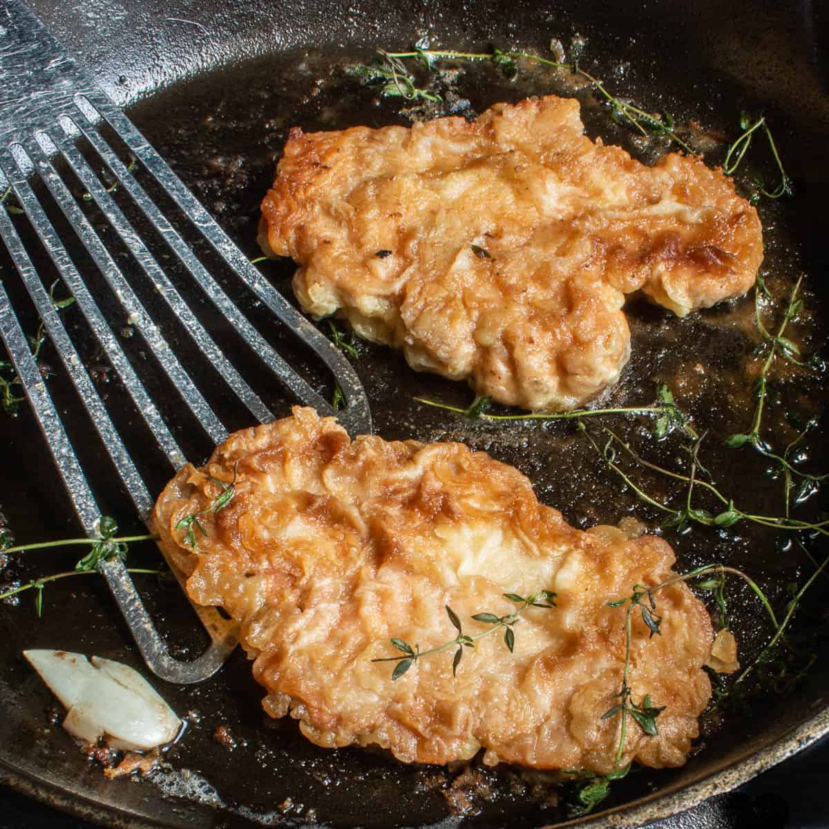 Cooking golden brown, breaded mushrooms in a cast iron skillet with garlic and thyme 