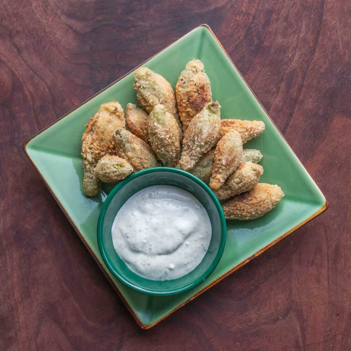 cornmeal fried milkweed pods on a plate with ranch dressing 