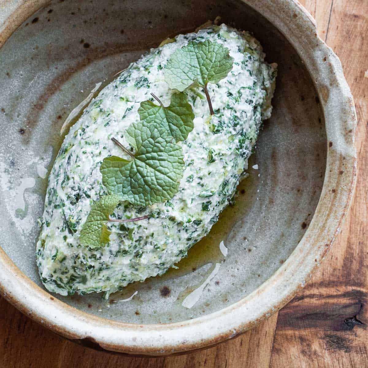 an oval scoop of ricotta cheese mixed with wild garlic mustard in a bowl 