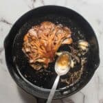 golden brown hen of the woods mushroom steak in a cast iron pan