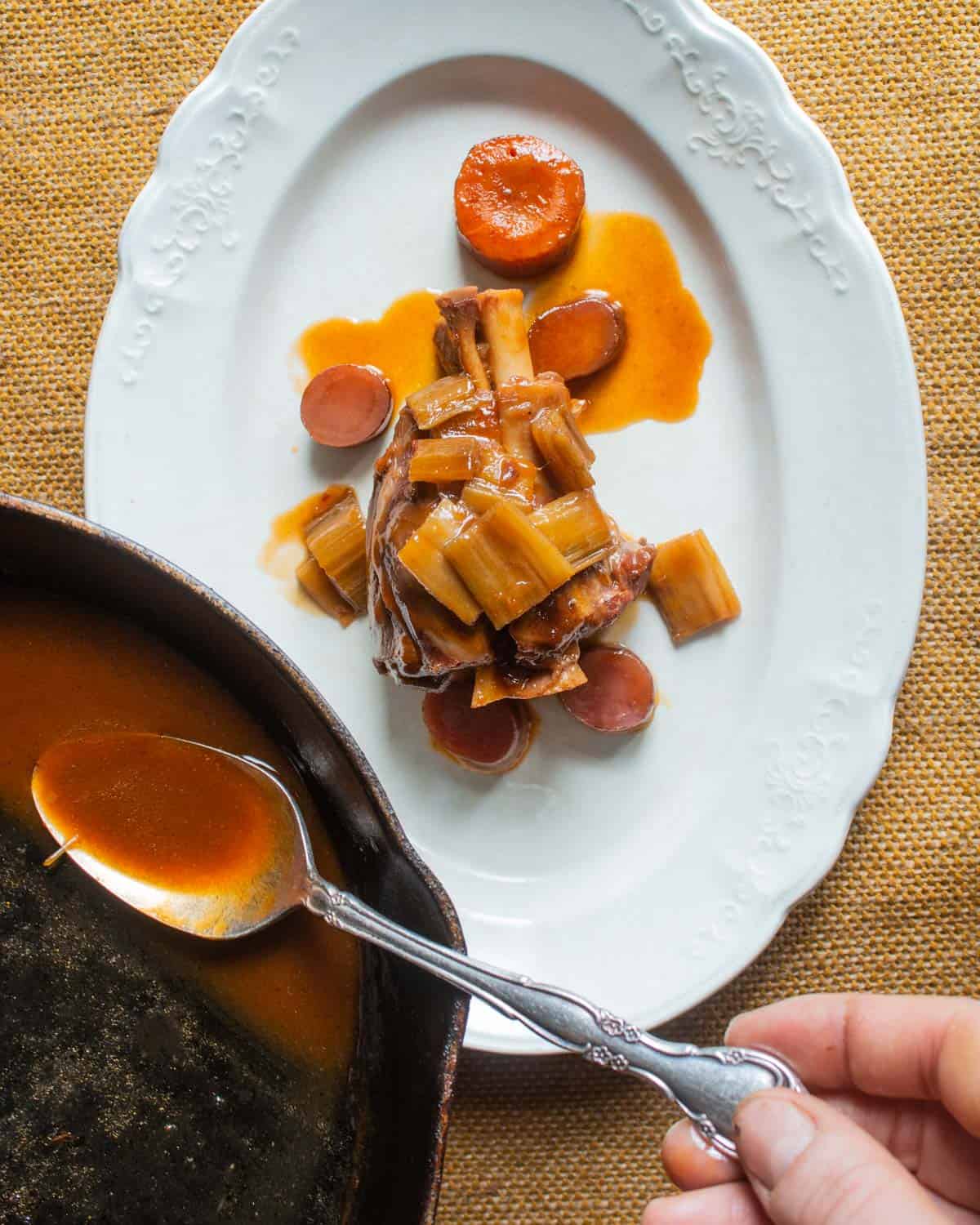 lamb shank with cardoons and tomato sauce on a plate. 