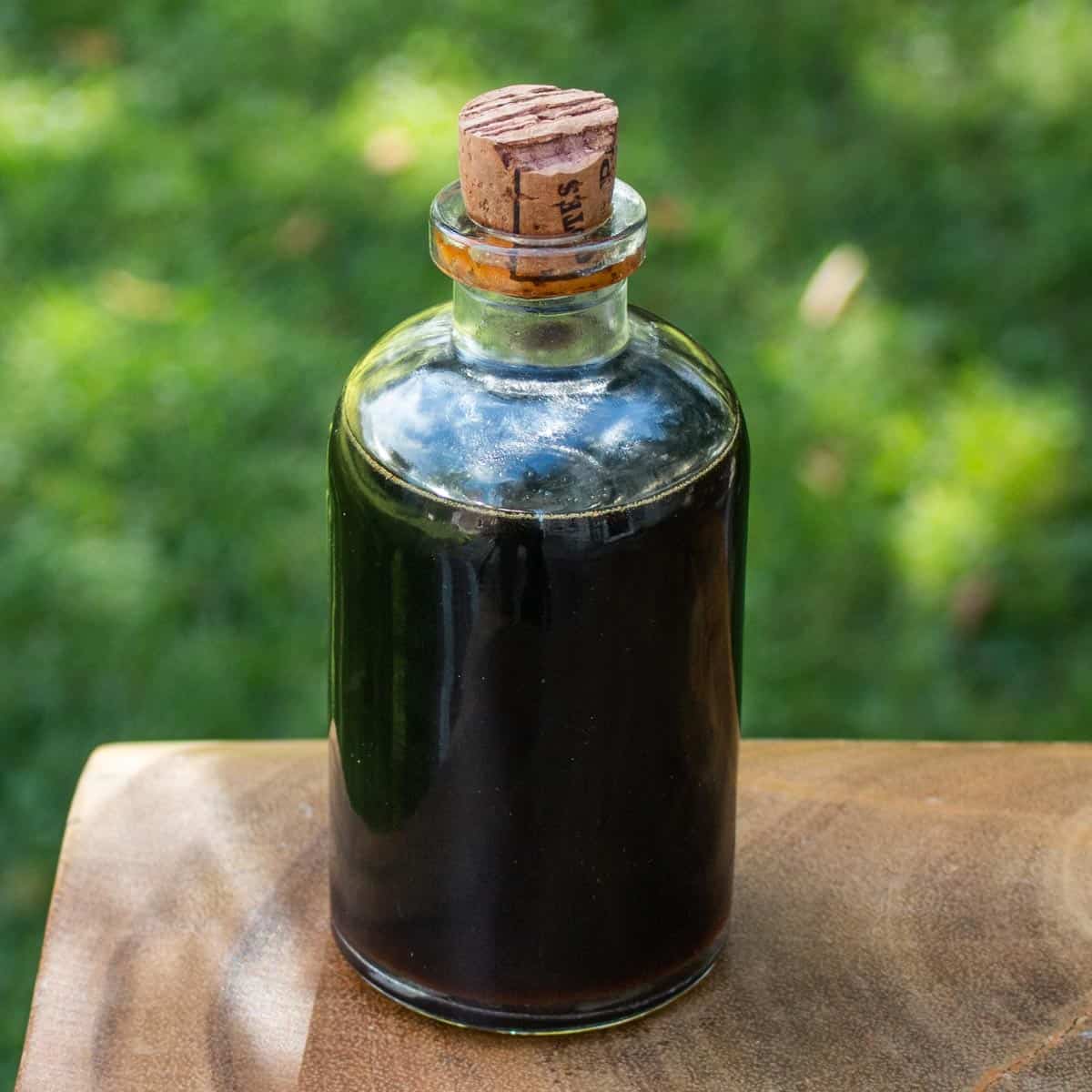 a glass jar of syrup outside on a table 