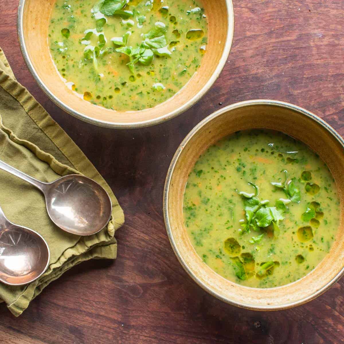 watercress soup in bowls with spoons on a napkin