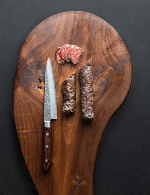 sliced salami on a black walnut wood board 