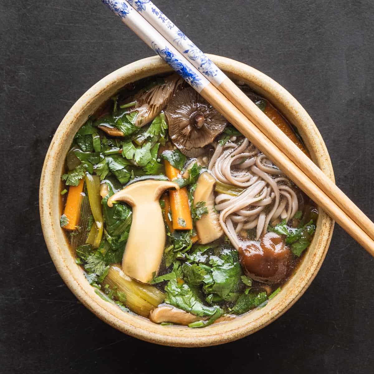 a bowl of wild mushroom noodle soup with chopsticks