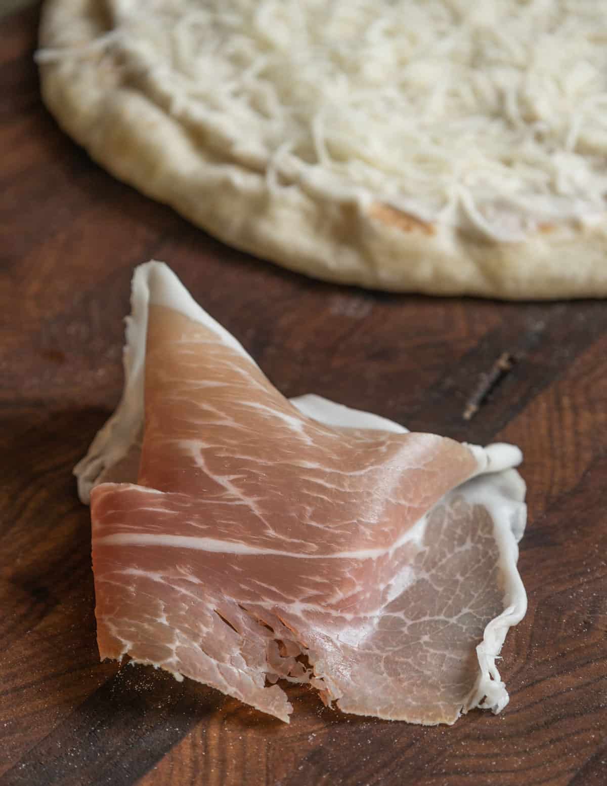 a slice of proscuitto next to a pizza crust