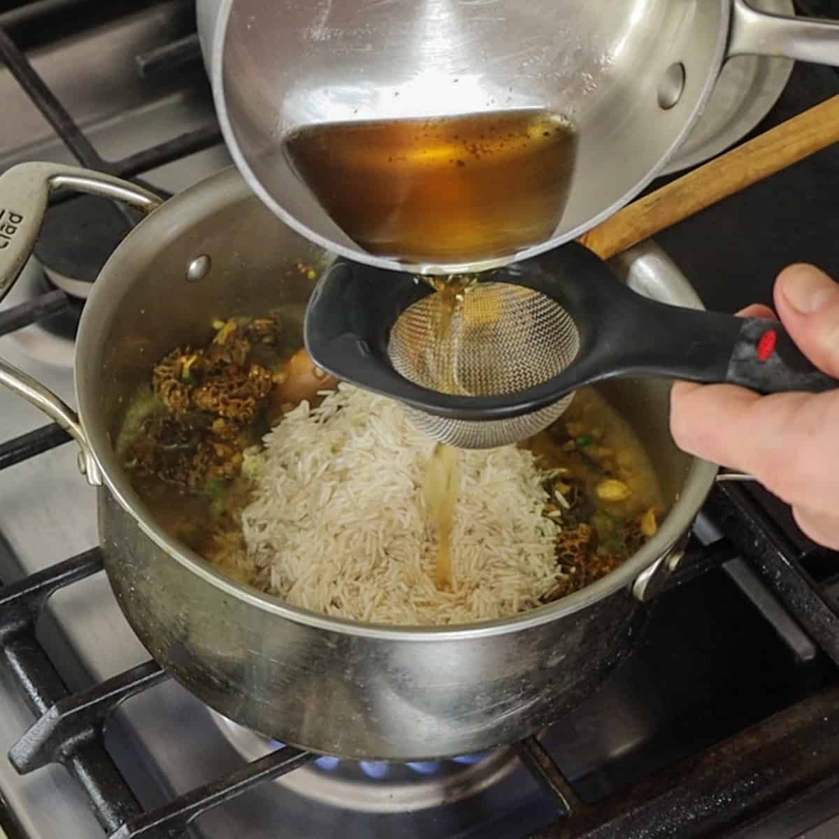 Adding mushroom liquid to rice, and spices for mushroom pilau