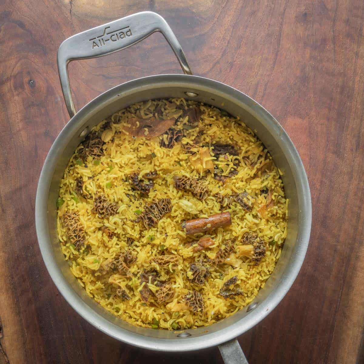 yellow Indian mushroom rice in a pot on a wood board