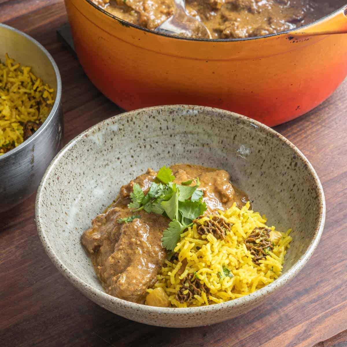 a bowl of yellow rice with curry next to a pot of curry