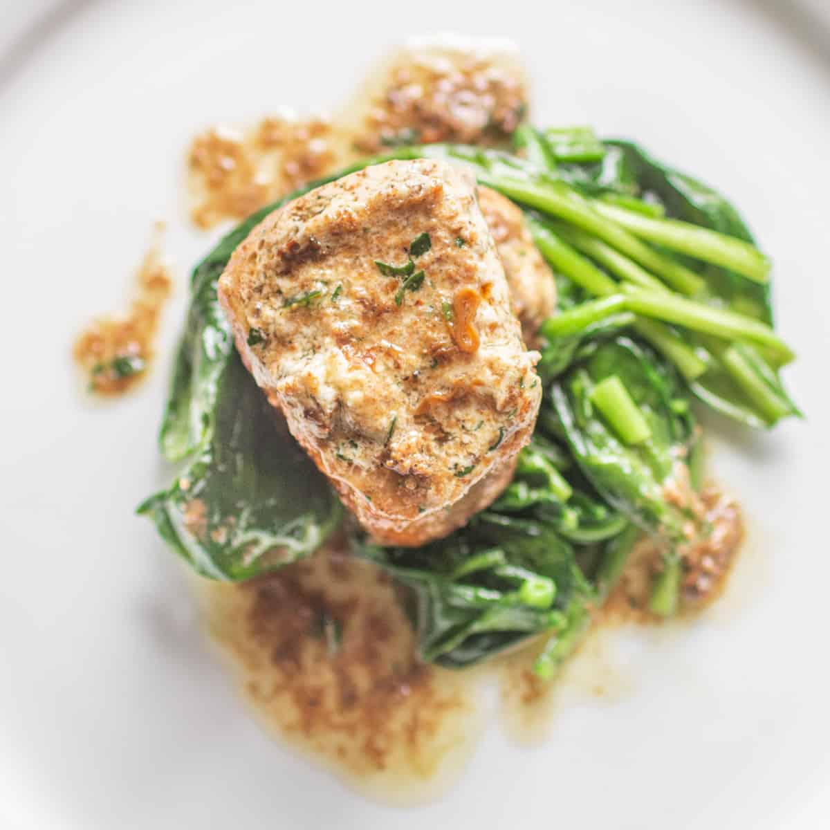 a piece of meat with mushroom butter melting on it over spinach