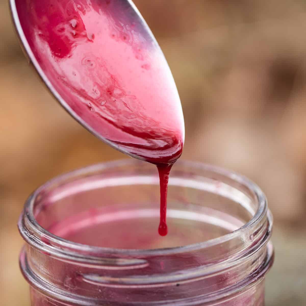 pink berry sauce dripping from a spoon 
