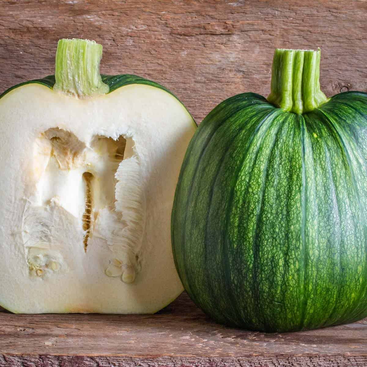 a green pumpkin cut in half showing seeds. 