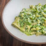 pasta in a white bowl with pesto sauce