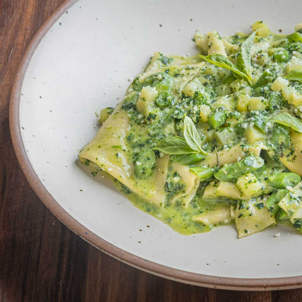 pasta in a white bowl with pesto sauce