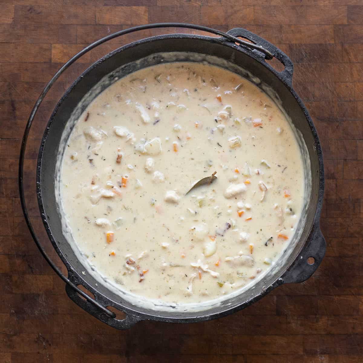 A pot of chowder with mushrooms on a wood board 
