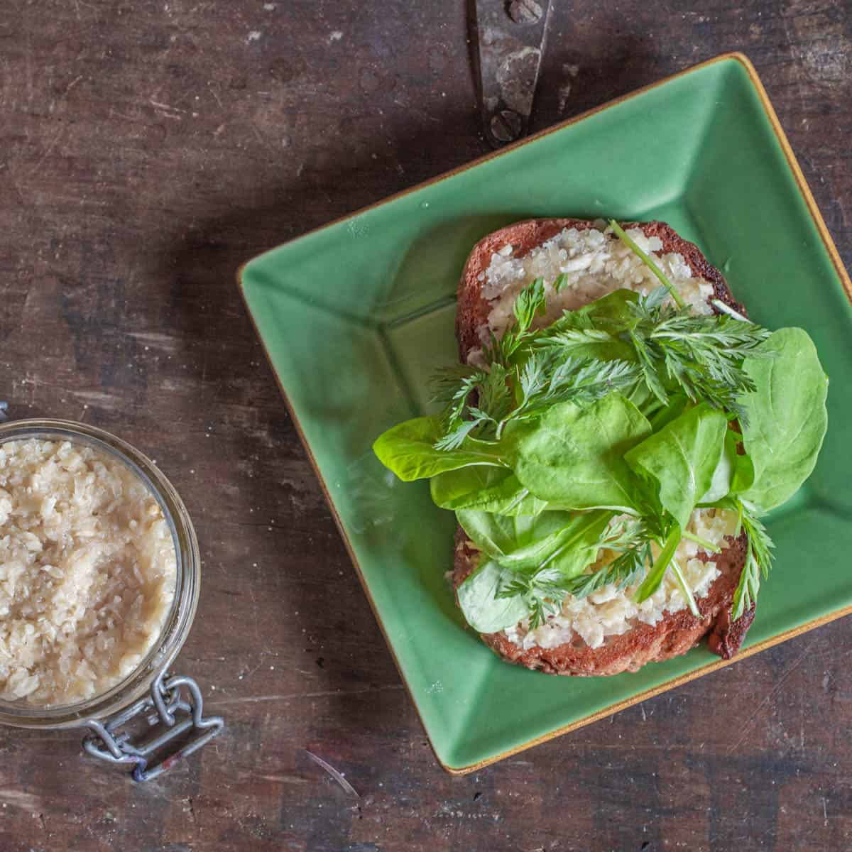 a piece of toast with spread, greens and herbs