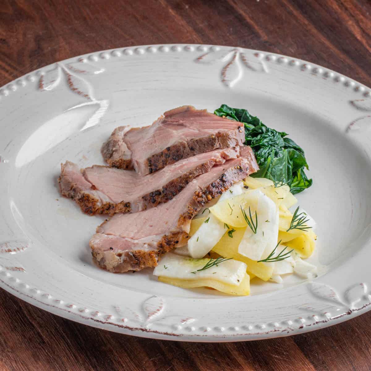 a cooked pork ribeye served with sauerkraut and apples.