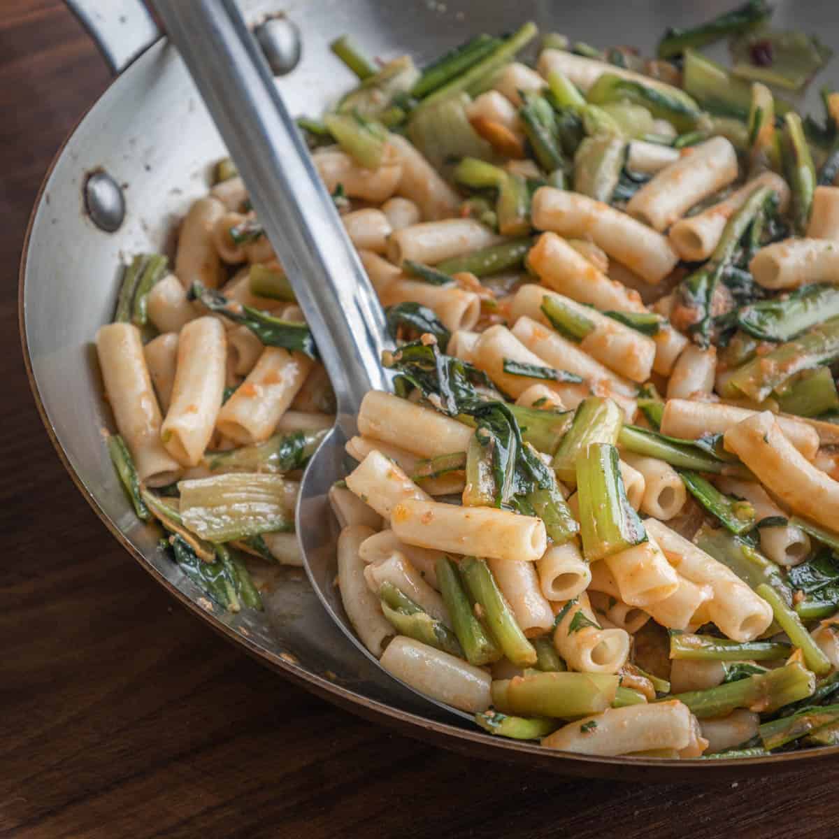 A pan of puntarelle pasta with tomato and pecorino cheese.