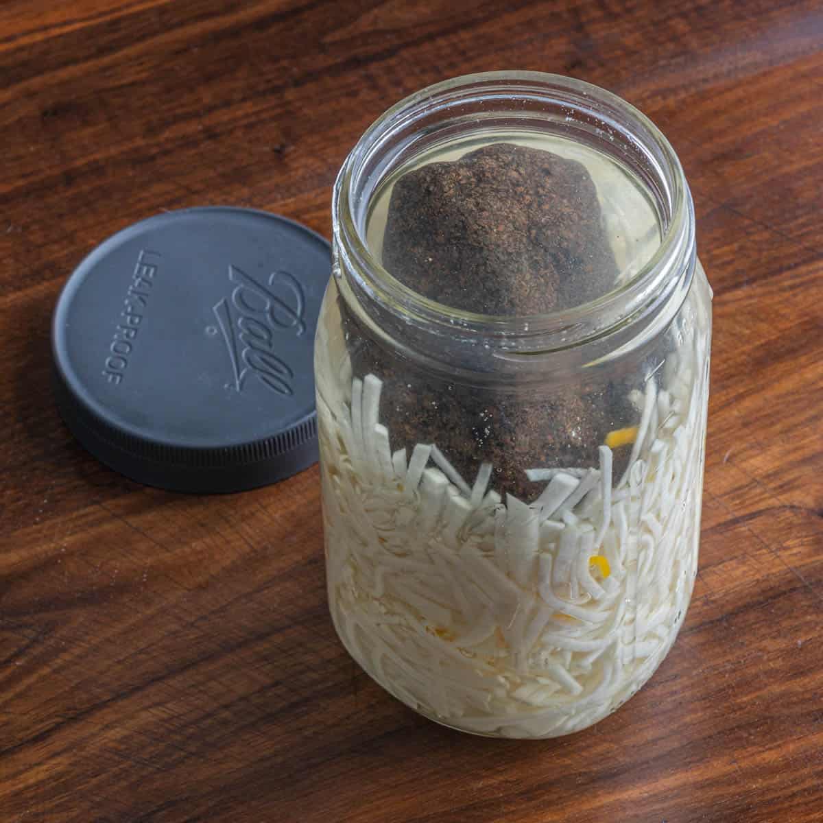 a mason jar filled with sliced turnips in brine held down with a rock.