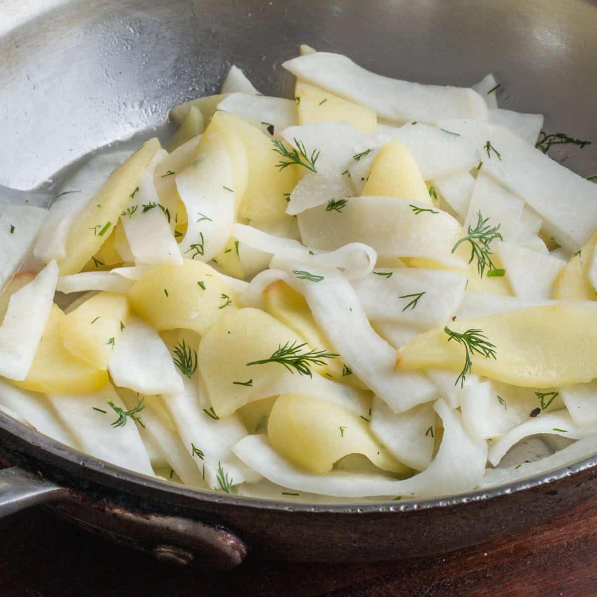 a pan of sliced turnips and apples with dill