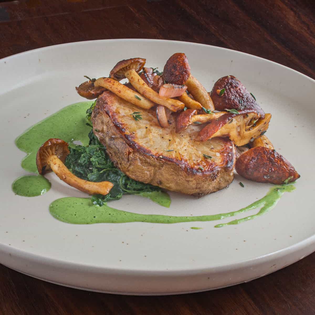 celeriac steak on a plate with herb sauce 