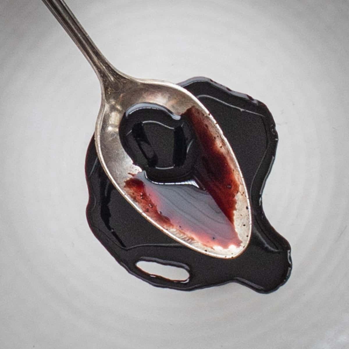 A black syrup on a white plate with a spoon