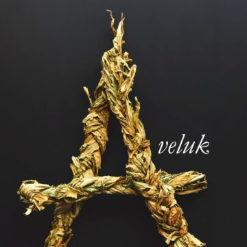 A dried braid of wild sorrel greens with text overlay spelling the word aveluk on a black background.