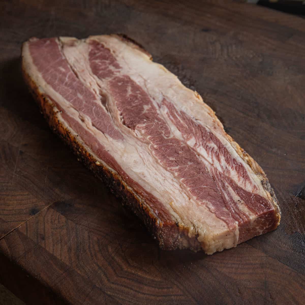 A thick slice of bacon or a bacon steak on a cutting board.