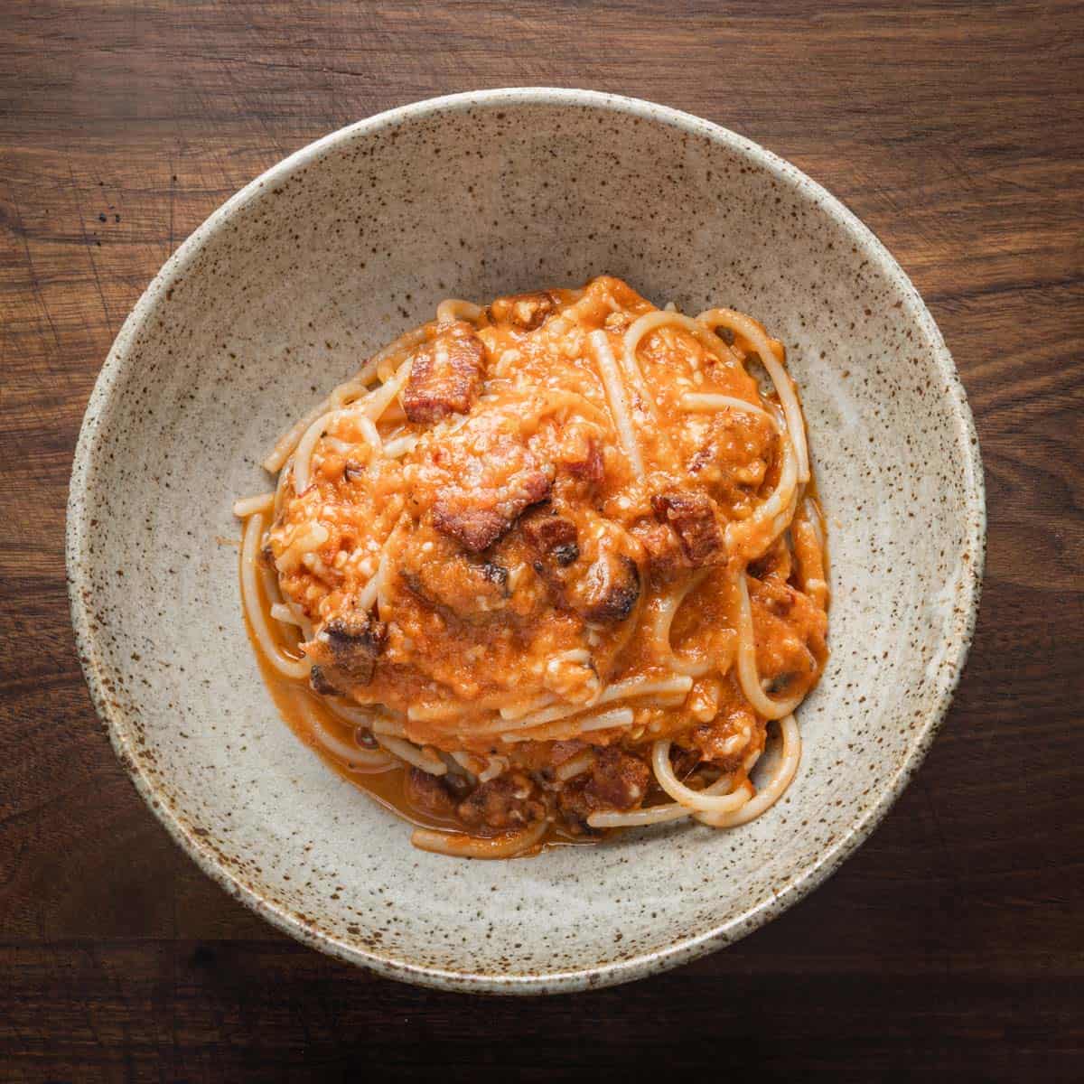 A pan of spaghetti with tomato sauce, cheese and beef bacon.