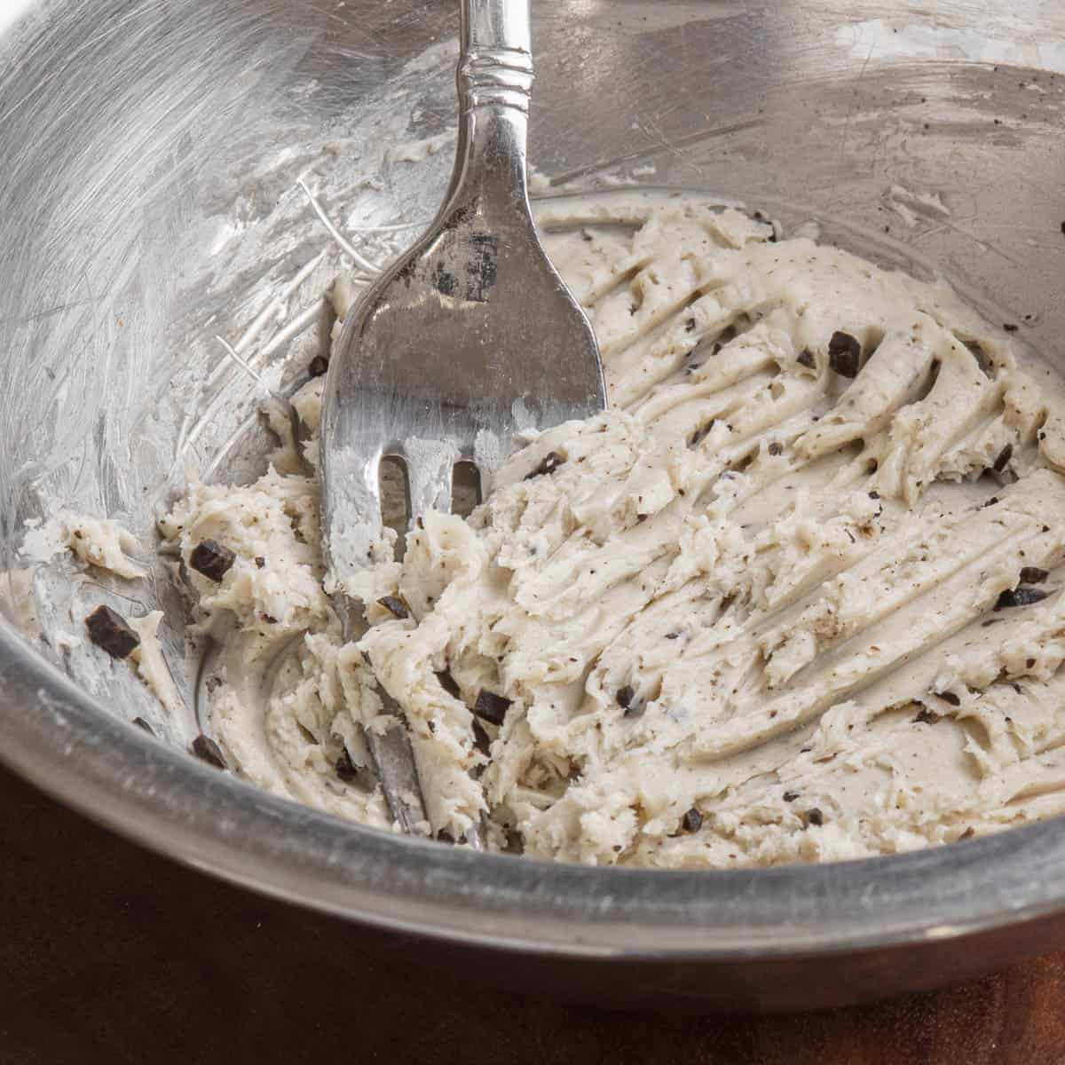 close up of mashing black truffle in a small metal bowl.