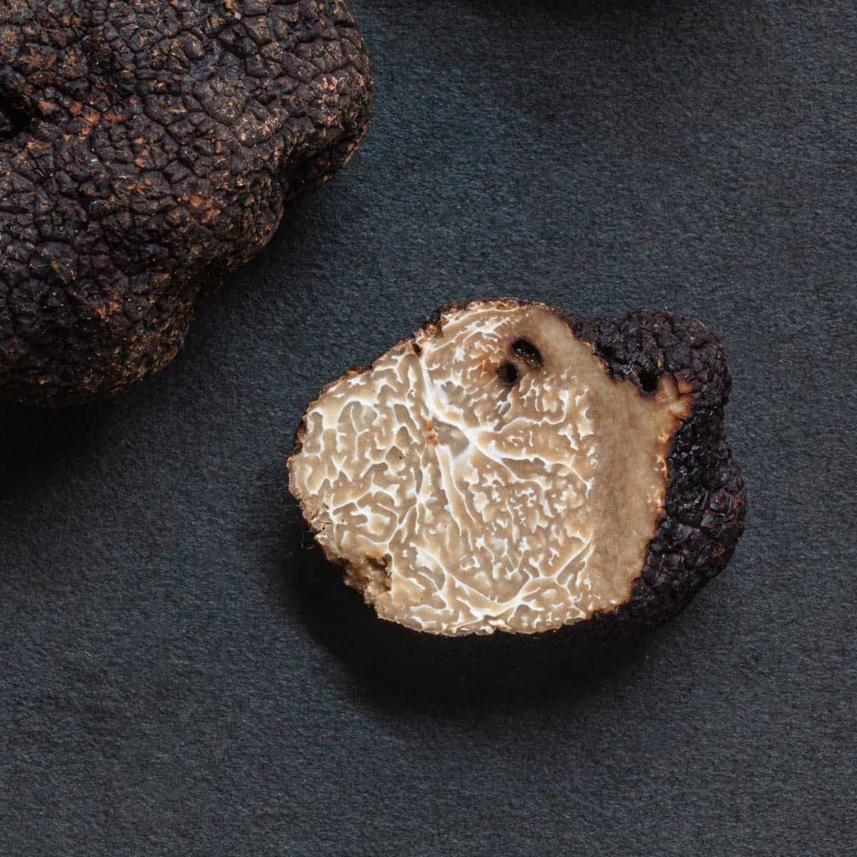black summer truffles cut in half on a black background