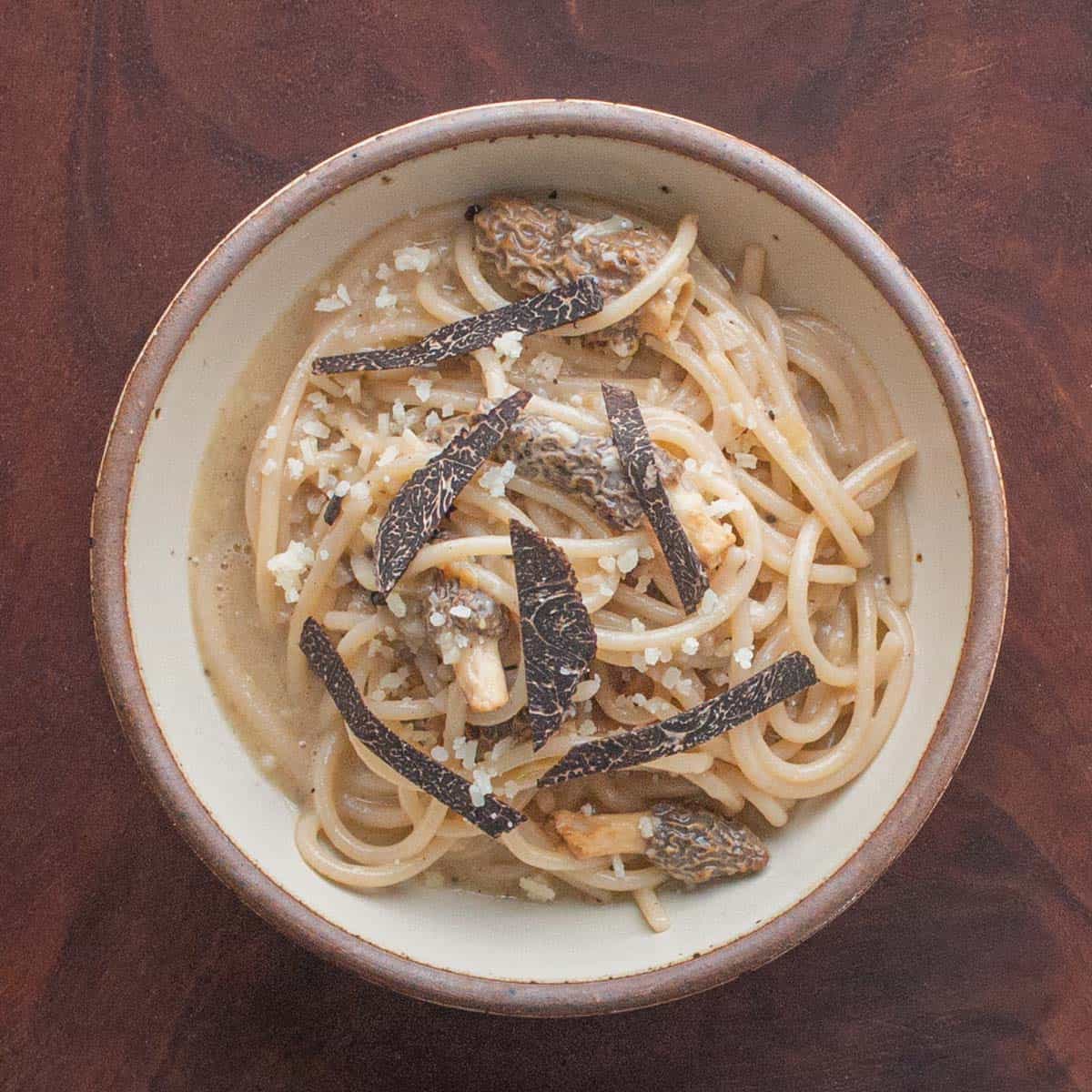 a ceramic bowl of pasta with truffle mushroom butter sauce