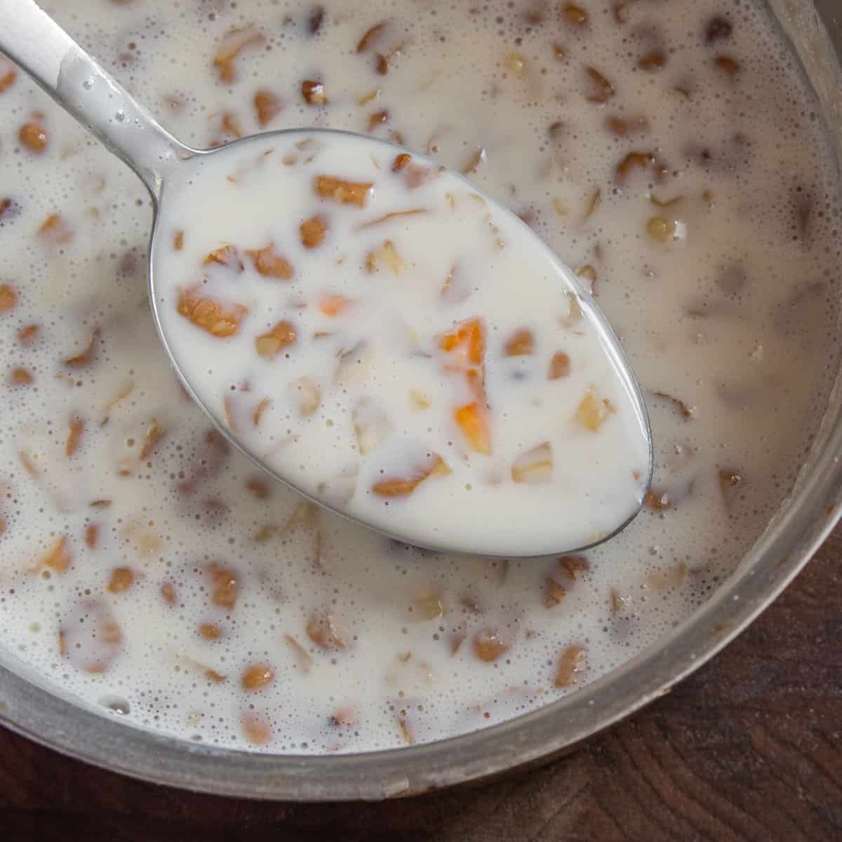 Cooked custard with black walnuts on a spoon.