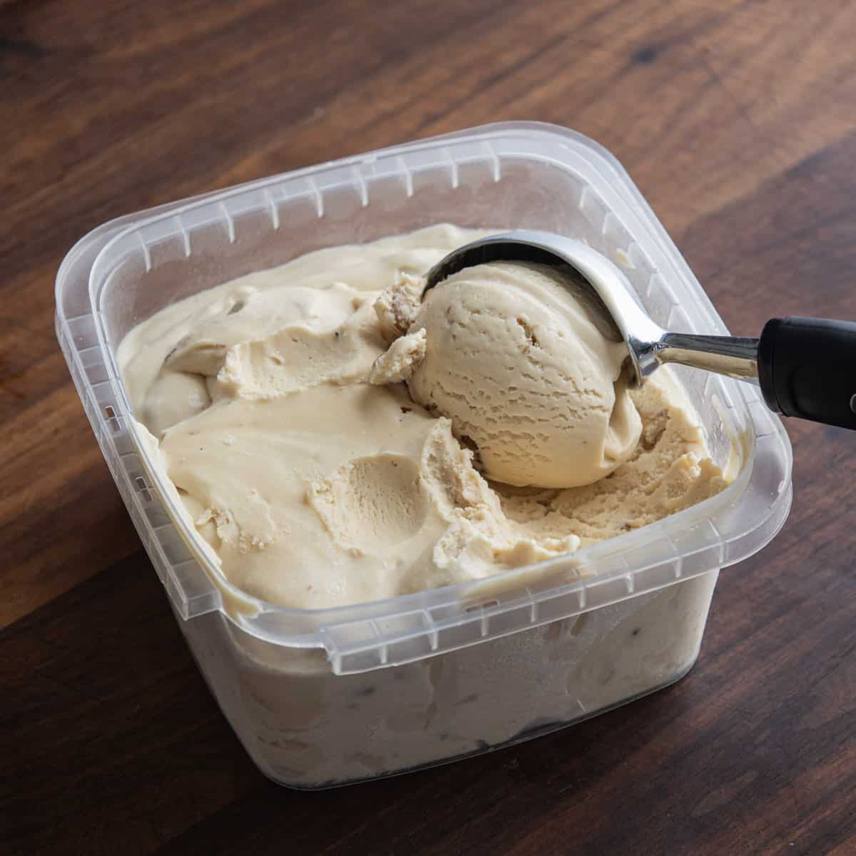 Scooping black walnut ice cream from a deli container.