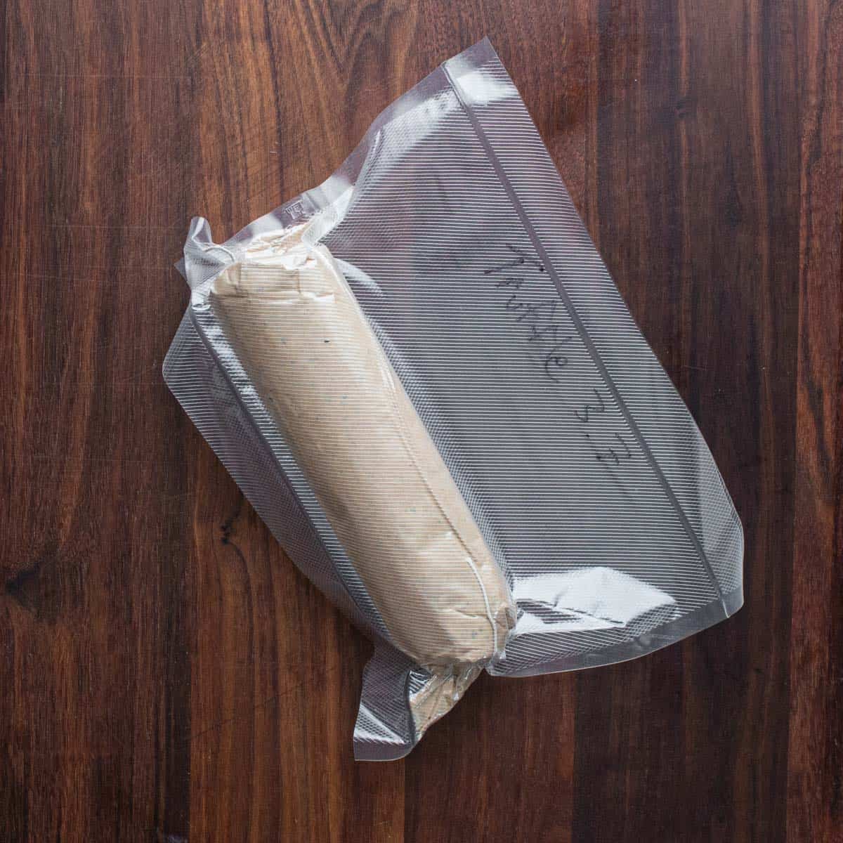 Frozen black truffle butter wrapped in parchment and vacuum sealed.