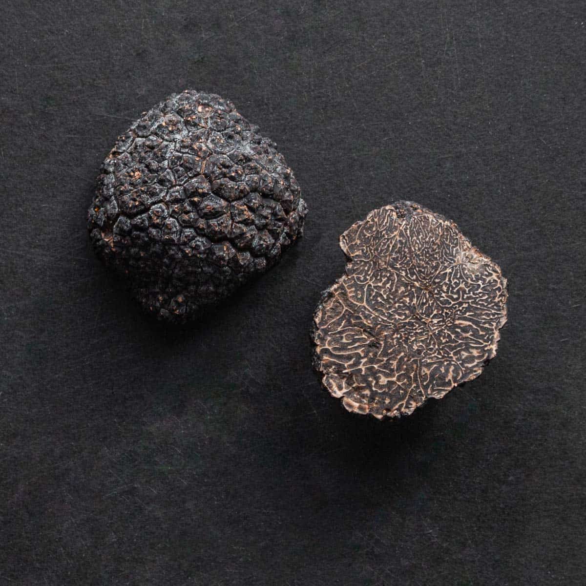 a black truffle cut in half on a black background. 