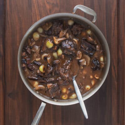 A large pot of lamb neck stew on a wooden background. 