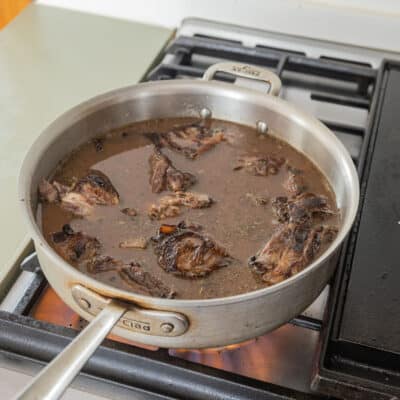 A wide pan with browned lamb neck, red wine and stock. 